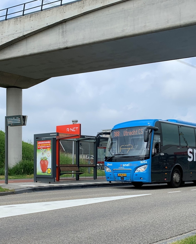 Een SnelBuzz staat bij een bushalte onder een viaduct